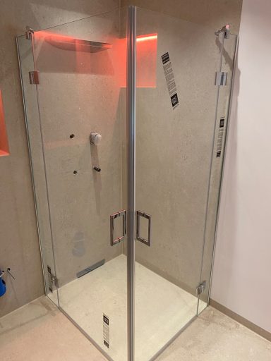 Moderne Duschkabine aus Glas mit silbernen Akzenten und Bodenfliesen.