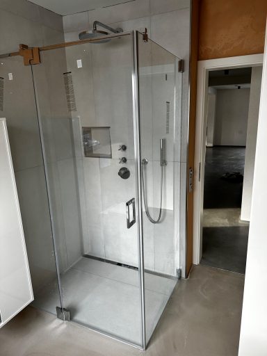 Moderne Duschkabine mit Glaswänden und grauem Bodenbelag.