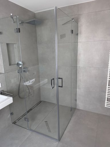 Moderne Dusche mit gläserner Kabine und grauen Fliesen.