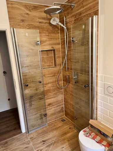 Moderne Dusche mit Glasabtrennungen und Holzverkleidung, hell und gepflegt.